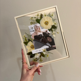 double-glass memorial frame with photographs, a handwritten “I love you” note and preserved pressed flowers.
