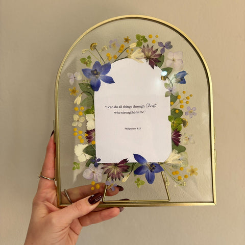 Gold arched double-glass frame with pressed flowers surrounding a Philippians 4:13 scripture keepsake.