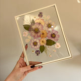 Gifting Just Bloom arrangement with pink and peach pressed flowers in an off-white double-glass frame by GLASH Designs