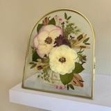 Gifting Just Bloom arrangement with pink and white pressed flowers in a gold arch double-glass frame by GLASH Designs