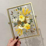 Gold double-glass frame with a yellow and white pressed flower arrangement by GLASH Designs