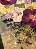 Burgundy and blush flowers being carefully arranged during the creation of a custom Just Bloom pressed flower frame.