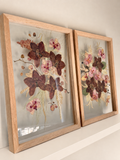 Just Bloom pressed flower frame held in natural sunlight, featuring preserved pink orchids and delicate greenery.