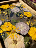 Close-up of preserved yellow, lilac and blush flowers inside a custom Just Bloom pressed flower frame.