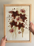 Two light oak Just Bloom pressed flower frames with preserved burgundy and pink orchids displayed together.
